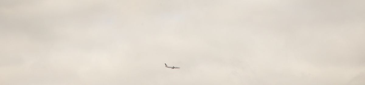 An airplane flying in a cloudly sky.